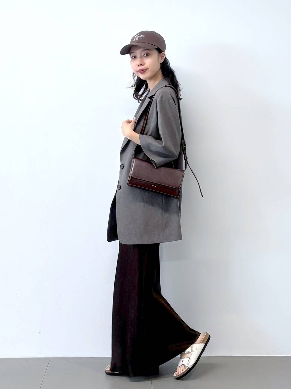 ホワイト系のサンダル、ブラック系のキャミソール、グレー系のテーラードジャケットを着用したレディースの春コーディネートの7枚目の写真