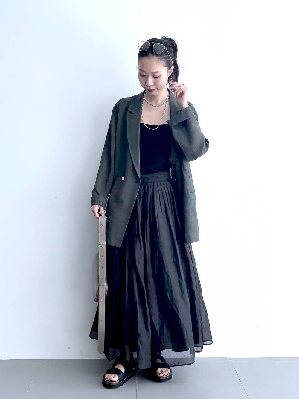 グレー系のテーラードジャケット、ブラック系のキャミソール、グリーン系のショルダーバッグを着用したレディースの夏コーディネートの8枚目の写真