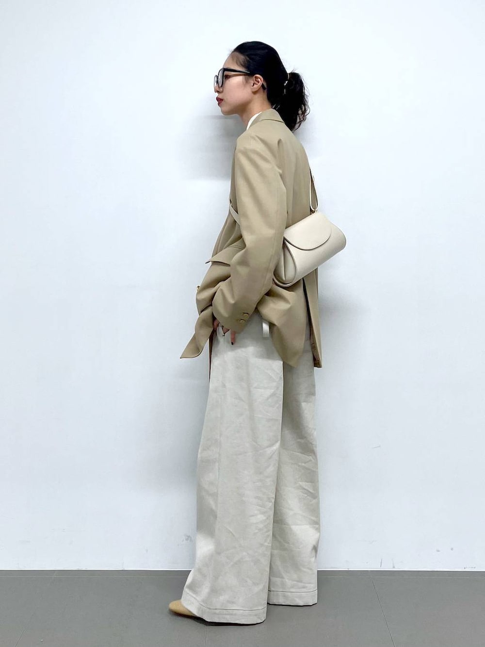 ホワイト系のショルダーバッグ、ベージュ系のテーラードジャケット、グレー系のサロペット/オーバーオールを着用したレディースの冬コーディネートの6枚目の写真