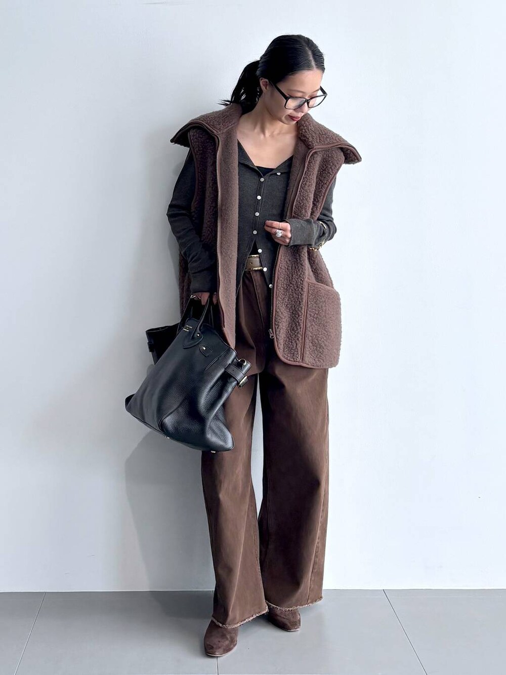 グレー系のカーディガン/ボレロ、ブラウン系のブーツ、ブラック系のハンドバッグを着用したレディースの秋コーディネートの3枚目の写真