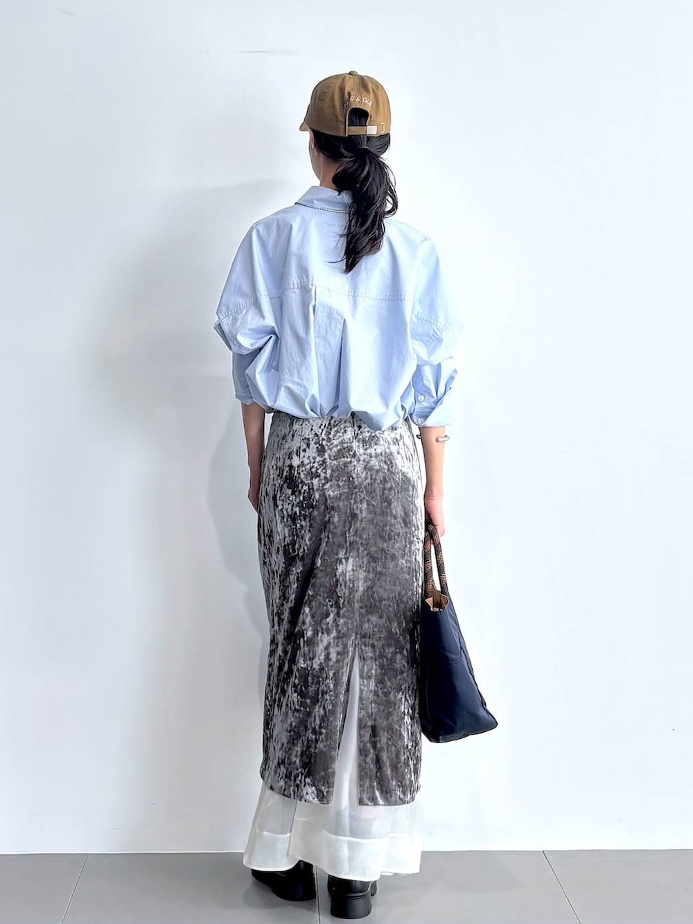 ブラック系のブーツ、グレー系のスカート、ブルー系のトートバッグを着用したレディースの秋コーディネートの4枚目の写真