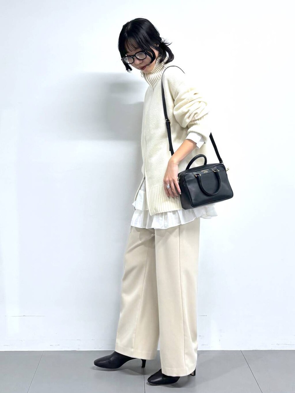 ブラック系のブーツ、ベージュ系のその他パンツ、ブラック系のボストンバッグを着用したレディースの冬コーディネートの3枚目の写真