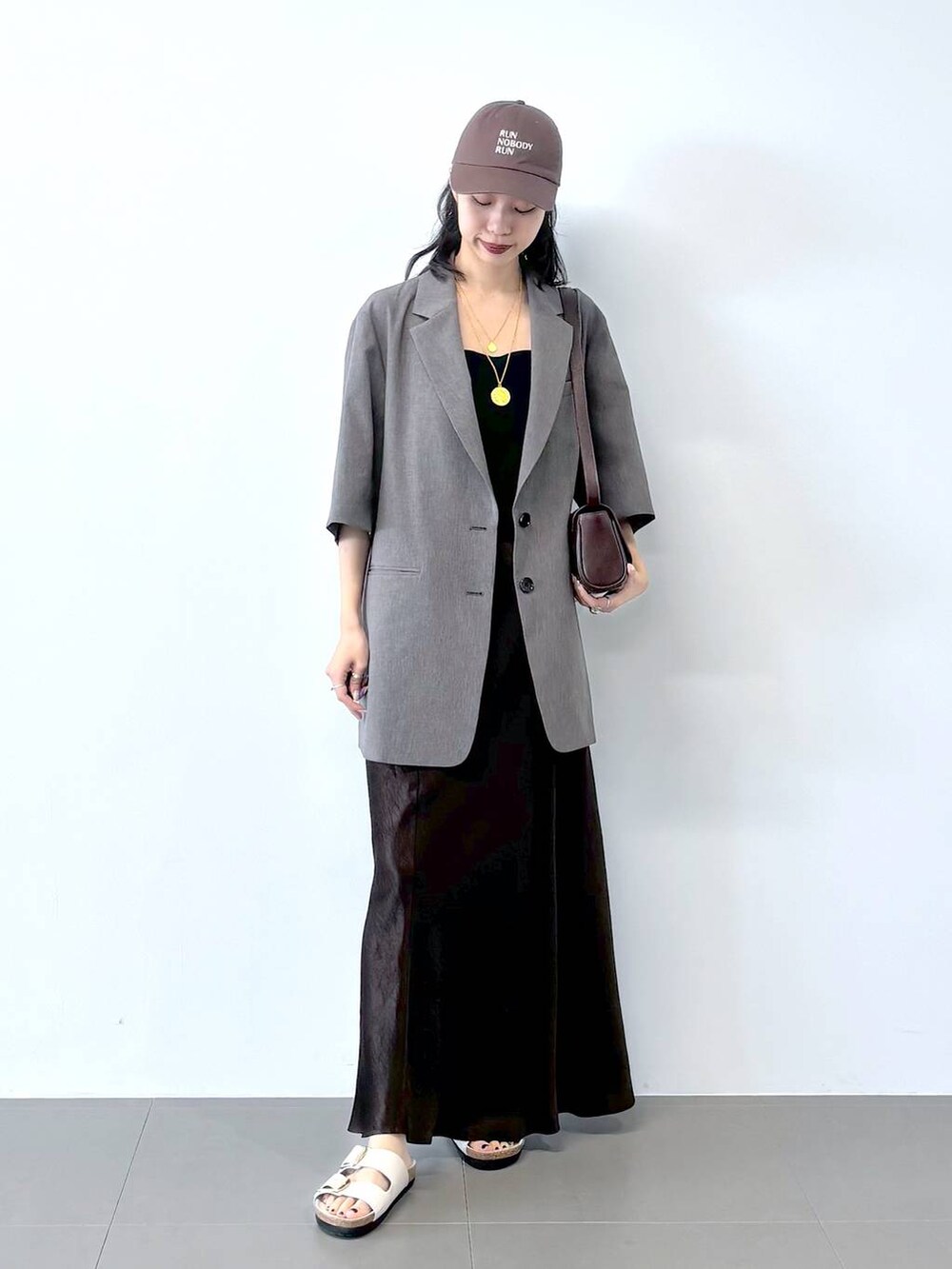 ホワイト系のサンダル、ブラック系のキャミソール、グレー系のテーラードジャケットを着用したレディースの春コーディネートの4枚目の写真