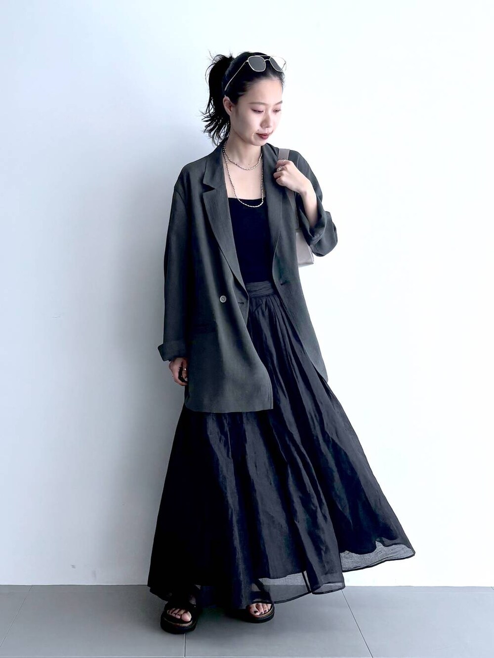 グレー系のテーラードジャケット、ブラック系のキャミソール、グリーン系のショルダーバッグを着用したレディースの夏コーディネートの5枚目の写真