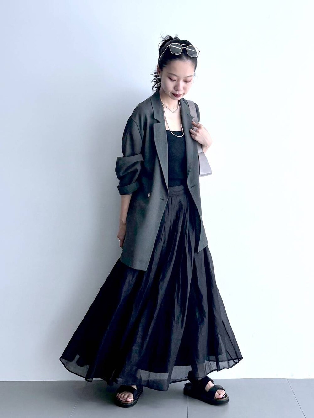 グレー系のテーラードジャケット、ブラック系のキャミソール、グリーン系のショルダーバッグを着用したレディースの夏コーディネートの6枚目の写真