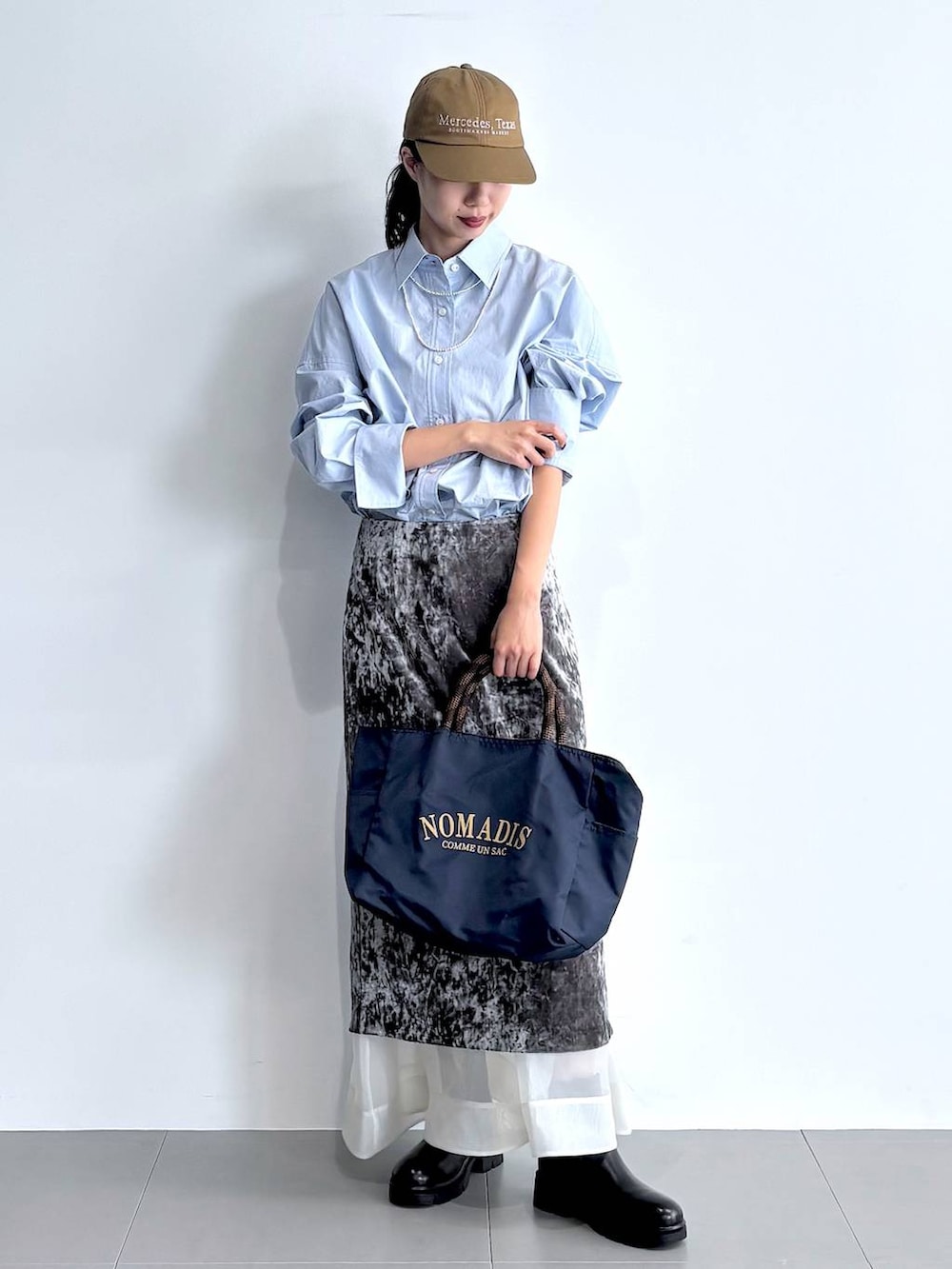 ブラック系のブーツ、グレー系のスカート、ブルー系のトートバッグを着用したレディースの秋コーディネートの2枚目の写真