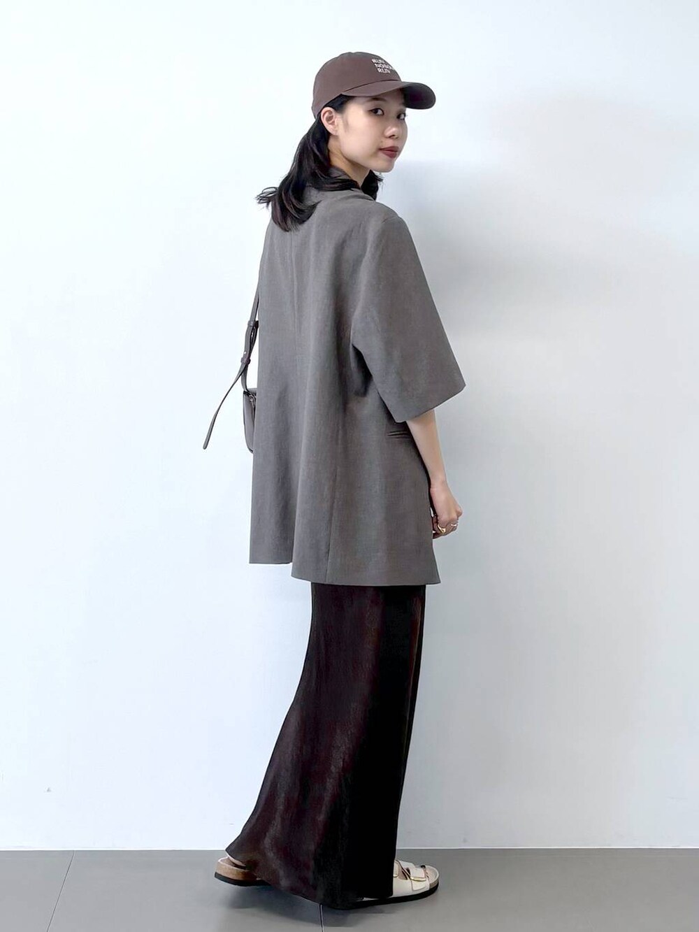 ホワイト系のサンダル、ブラック系のキャミソール、グレー系のテーラードジャケットを着用したレディースの春コーディネートの3枚目の写真