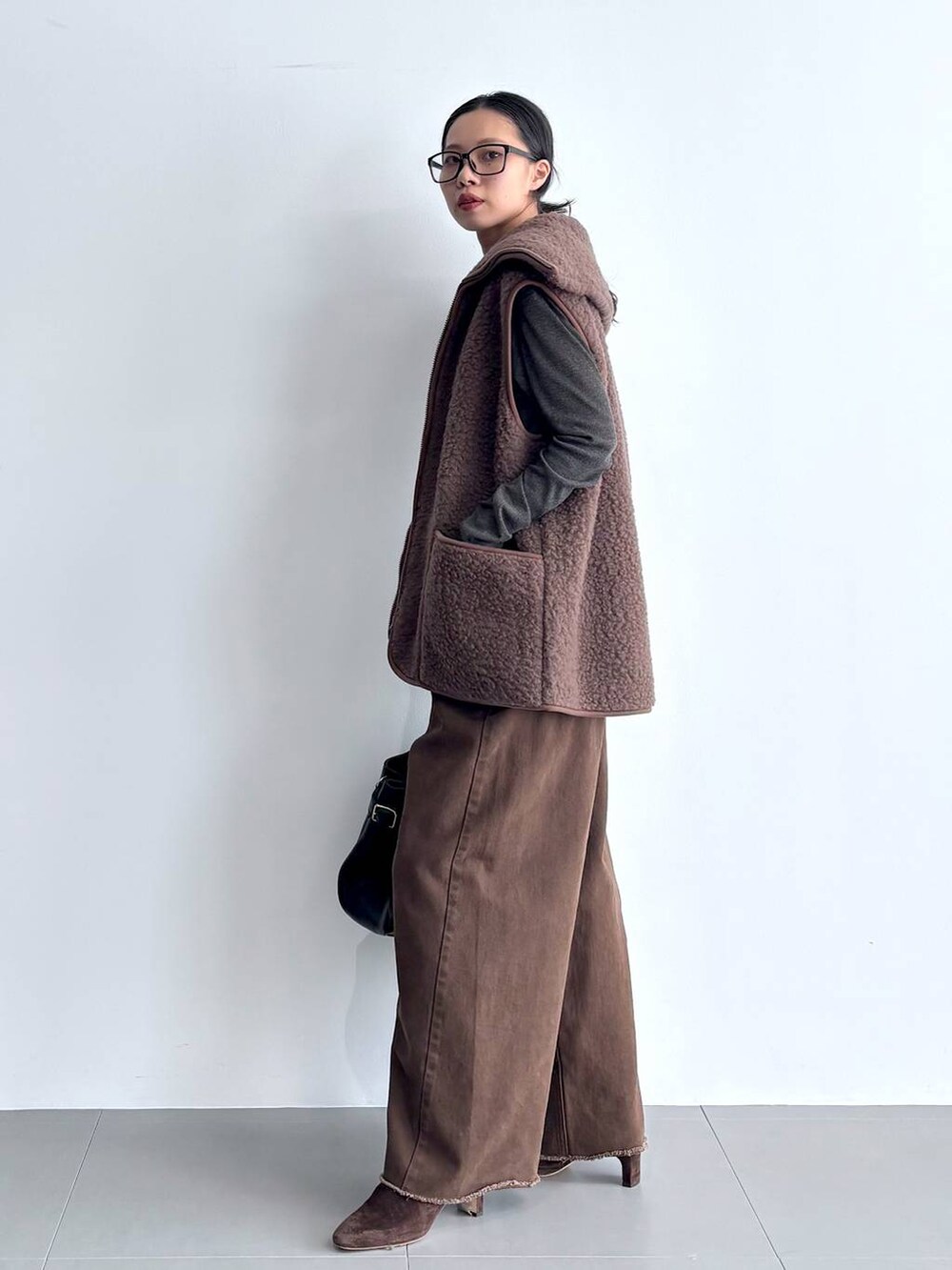 グレー系のカーディガン/ボレロ、ブラウン系のブーツ、ブラック系のハンドバッグを着用したレディースの秋コーディネートの6枚目の写真