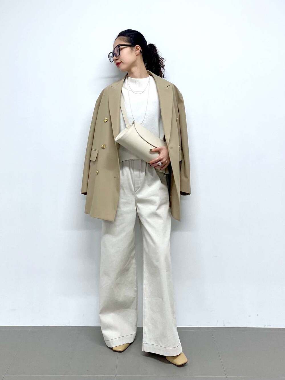 ホワイト系のショルダーバッグ、ベージュ系のテーラードジャケット、グレー系のサロペット/オーバーオールを着用したレディースの冬コーディネートの2枚目の写真