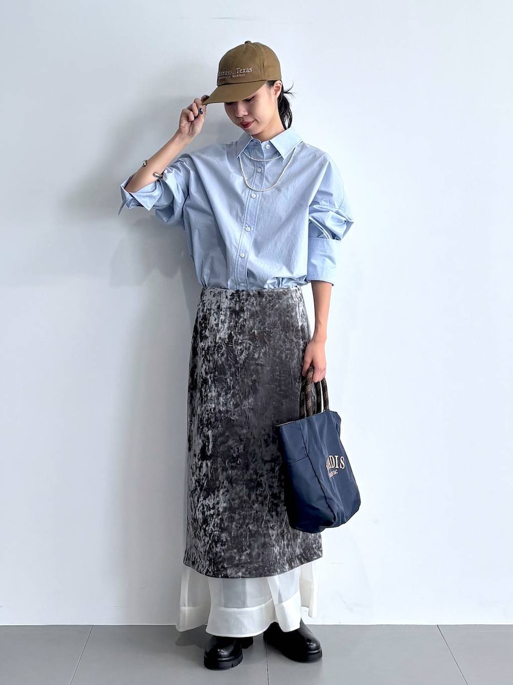 ブラック系のブーツ、グレー系のスカート、ブルー系のトートバッグを着用したレディースの秋コーディネートの5枚目の写真