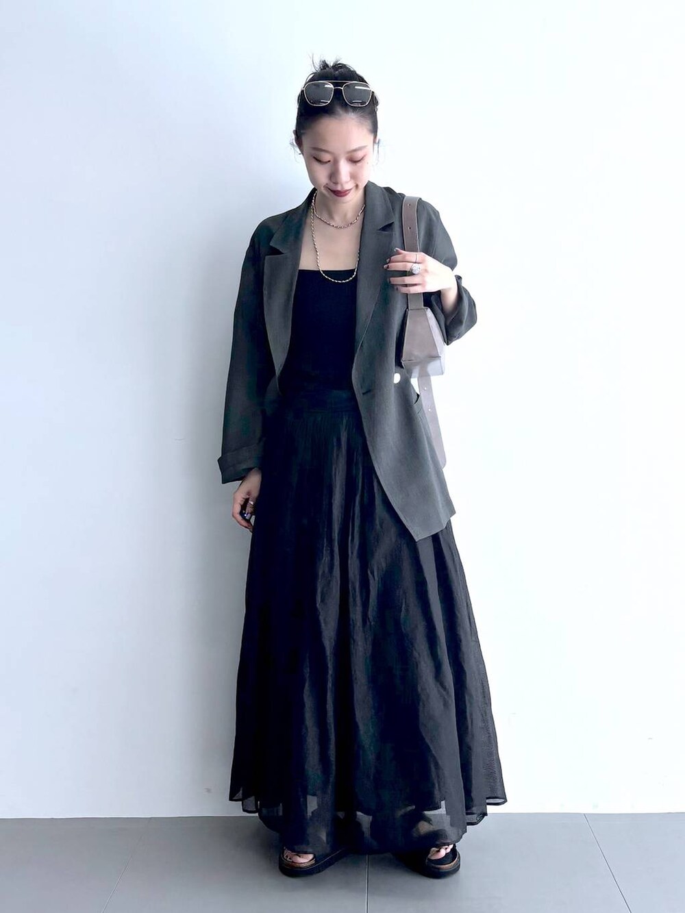 グレー系のテーラードジャケット、ブラック系のキャミソール、グリーン系のショルダーバッグを着用したレディースの夏コーディネートの4枚目の写真