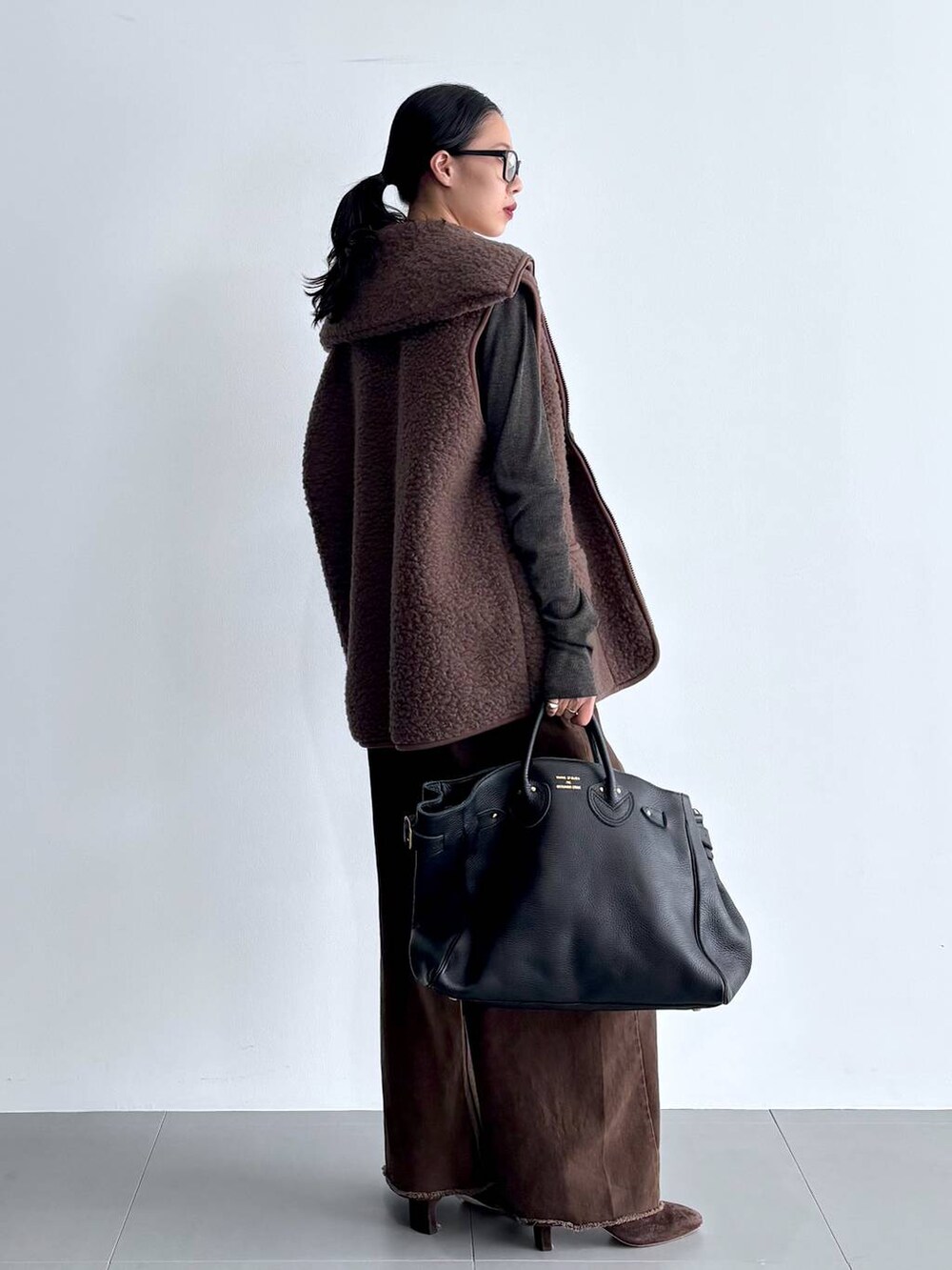 グレー系のカーディガン/ボレロ、ブラウン系のブーツ、ブラック系のハンドバッグを着用したレディースの秋コーディネートの5枚目の写真