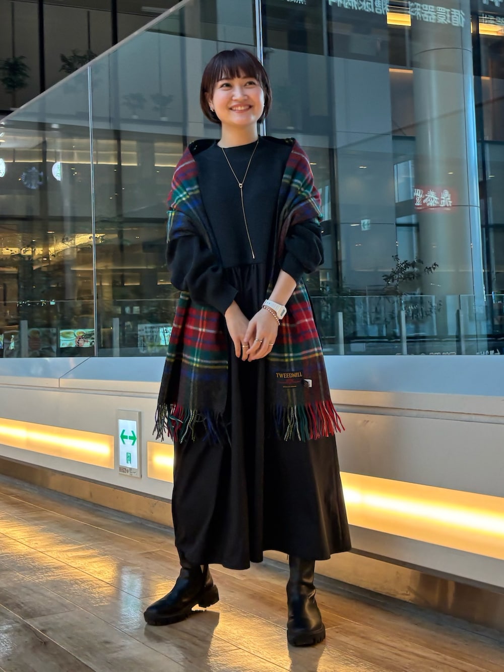 ブラック系のブーツ、ブラック系のワンピース、グレー系のマフラーを着用したレディースの秋コーディネートの3枚目の写真