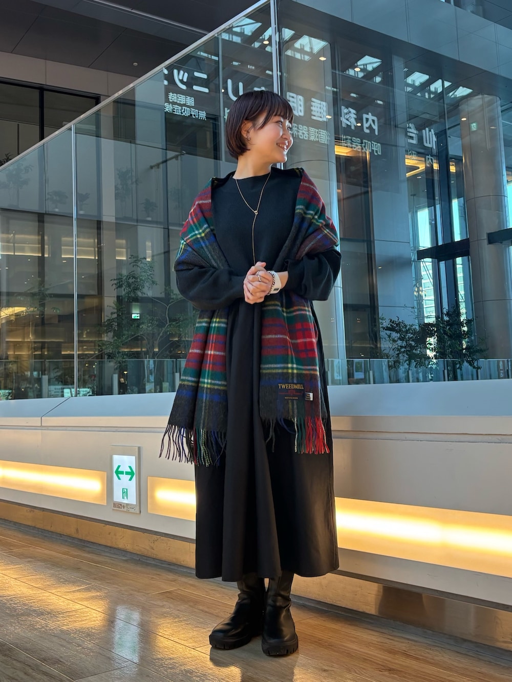 ブラック系のブーツ、ブラック系のワンピース、グレー系のマフラーを着用したレディースの秋コーディネートの4枚目の写真