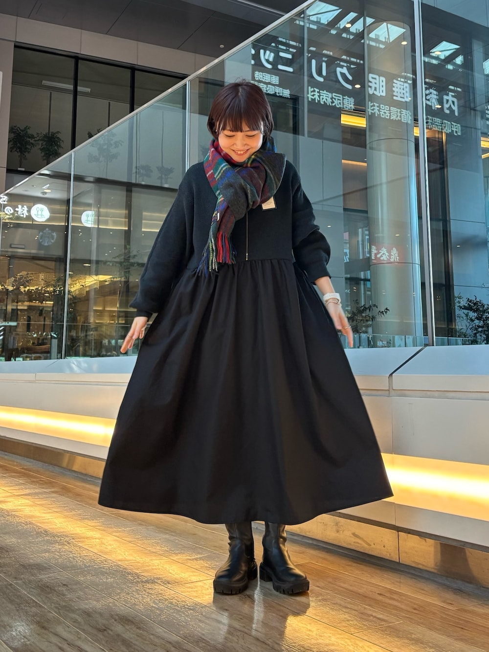 ブラック系のブーツ、ブラック系のワンピース、グレー系のマフラーを着用したレディースの秋コーディネートの2枚目の写真