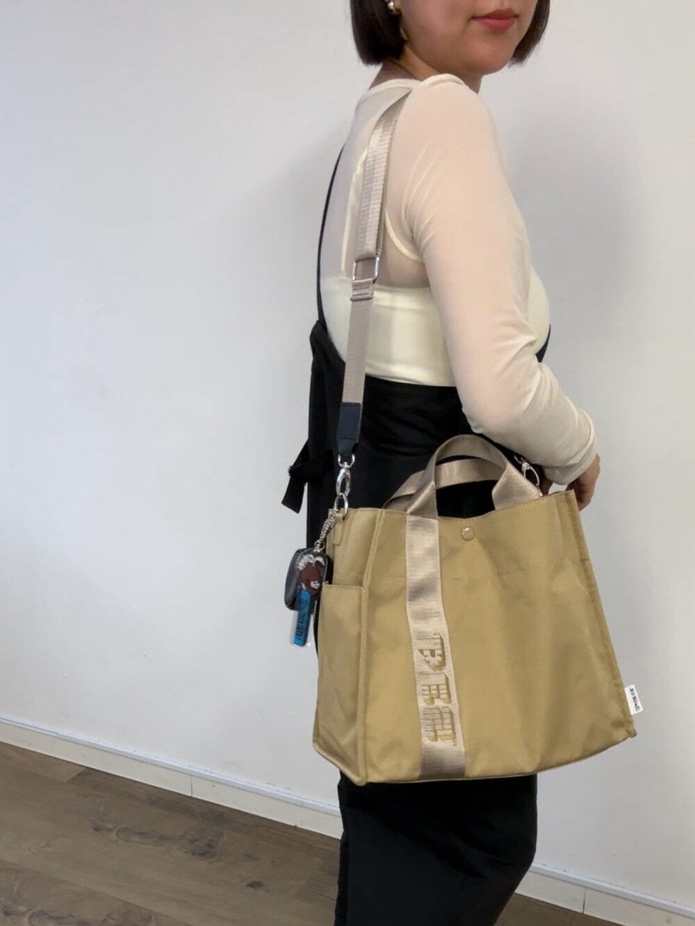 ベージュ系のトートバッグ、ブラック系のサロペット/オーバーオール、シルバー系のネックレスを着用したレディースの春コーディネートの4枚目の写真