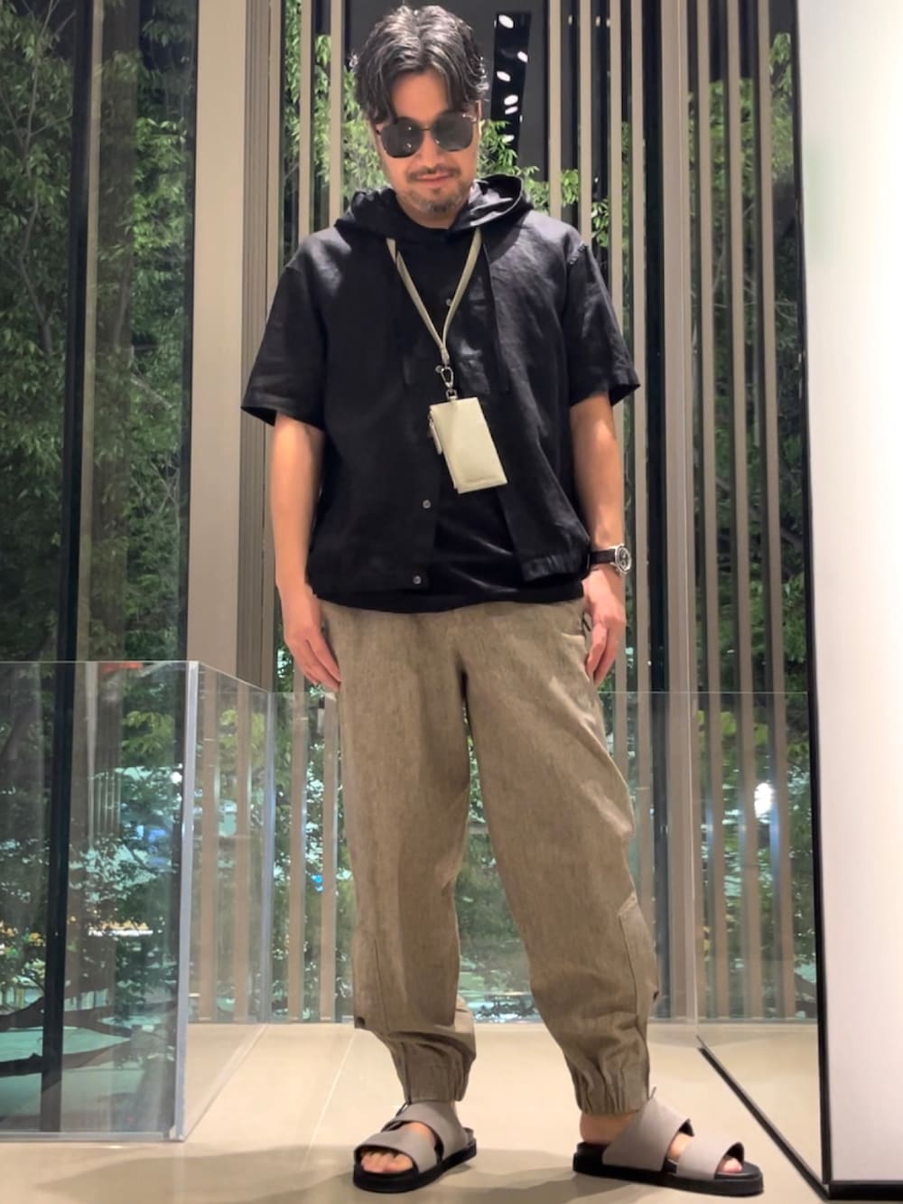 グレー系のサンダル、ブラック系のTシャツ/カットソー、イエロー系のパスケースを着用したメンズの春コーディネートの2枚目の写真