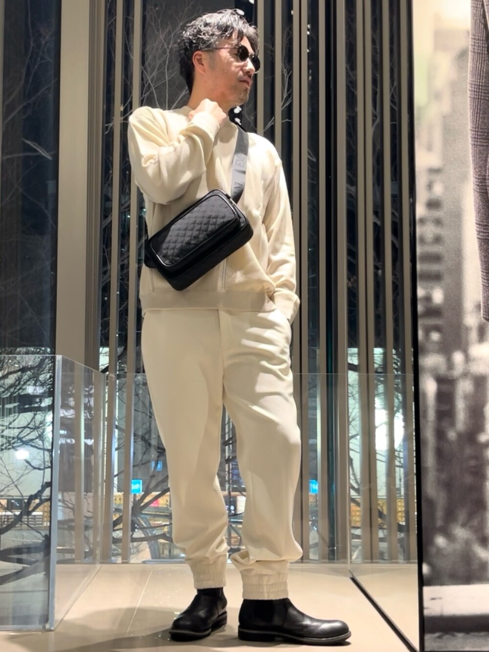 ベージュ系のニット/セーター、ブラック系のショルダーバッグ、ブラック系のブーツを着用したメンズの冬コーディネートの2枚目の写真