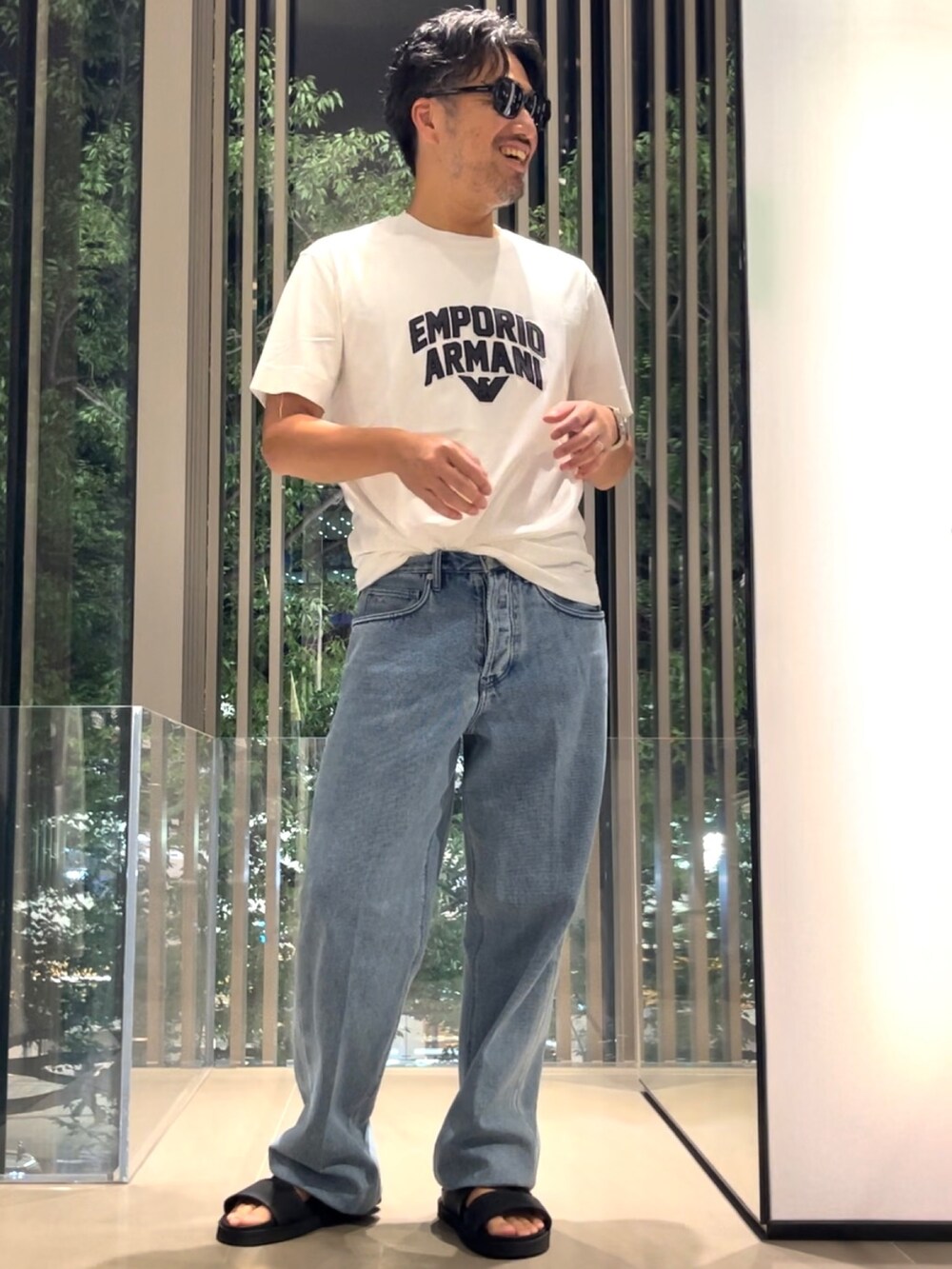 ブラック系のサンダル、ブルー系のデニムパンツ、ホワイト系のTシャツ/カットソーを着用したメンズの夏コーディネートの2枚目の写真