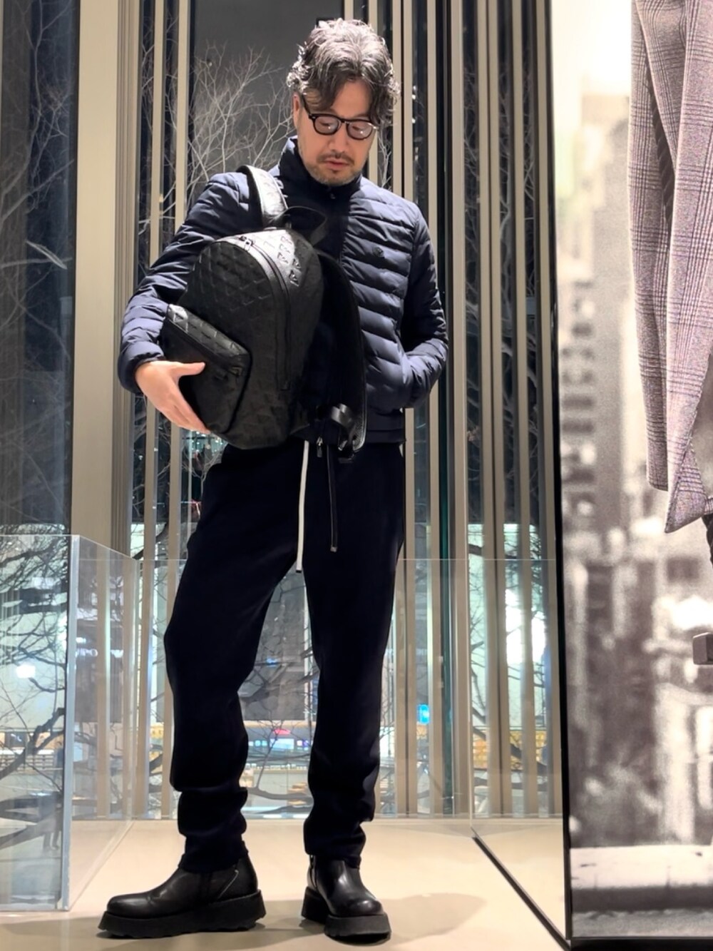 ブラック系のダウンジャケット/コート、ホワイト系のTシャツ/カットソー、ブルー系のスウェットパンツを着用したメンズの冬コーディネートの2枚目の写真