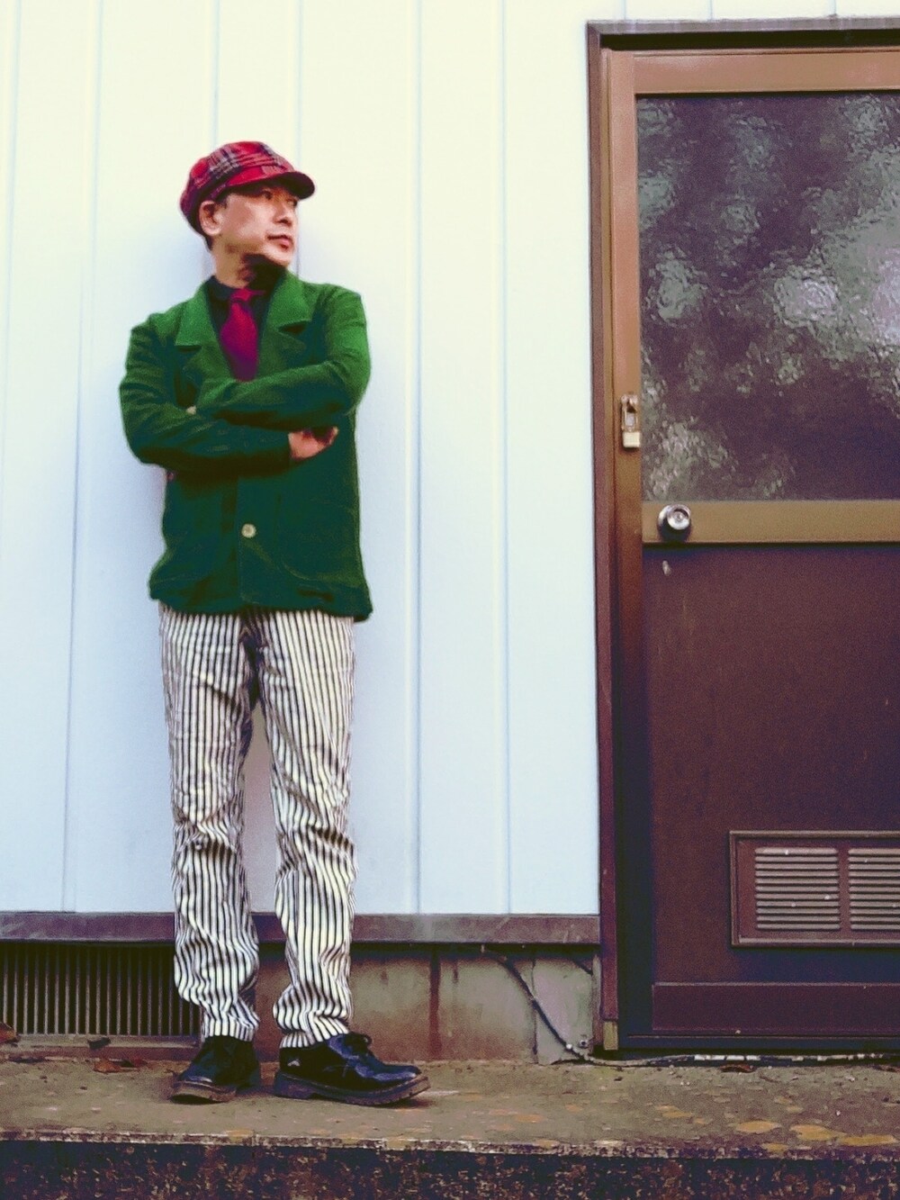 グリーン系のテーラードジャケット、ホワイト系のスラックス、レッド系のネクタイを着用したメンズの秋コーディネートの2枚目の写真