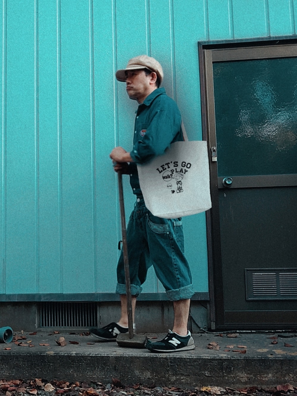 オレンジ系のパーカー、ブルー系のTシャツ/カットソー、ホワイト系のトートバッグを着用したメンズの秋コーディネートの2枚目の写真