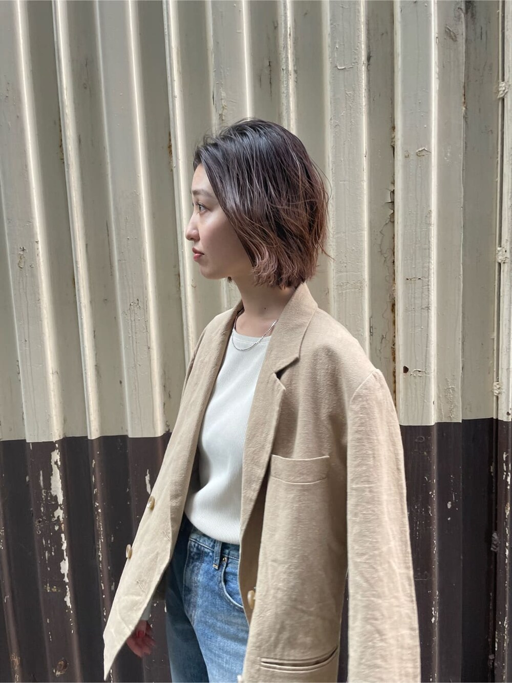 ベージュ系のテーラードジャケット、ホワイト系のTシャツ/カットソー、ブルー系のデニムパンツを着用したレディースの春コーディネートの3枚目の写真