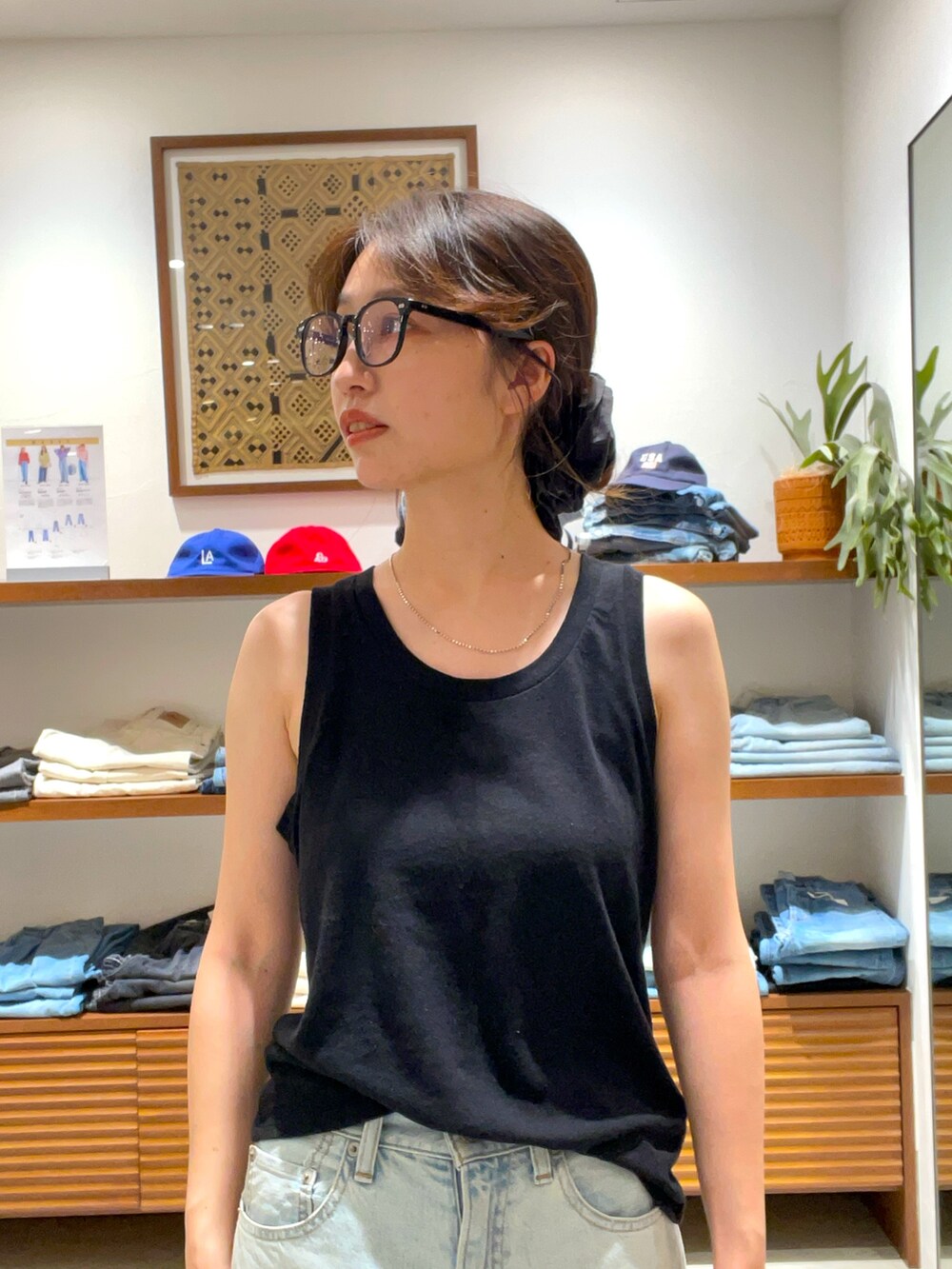 ブラック系のタンクトップ、ブルー系のデニムパンツを着用したレディースの夏コーディネートの4枚目の写真