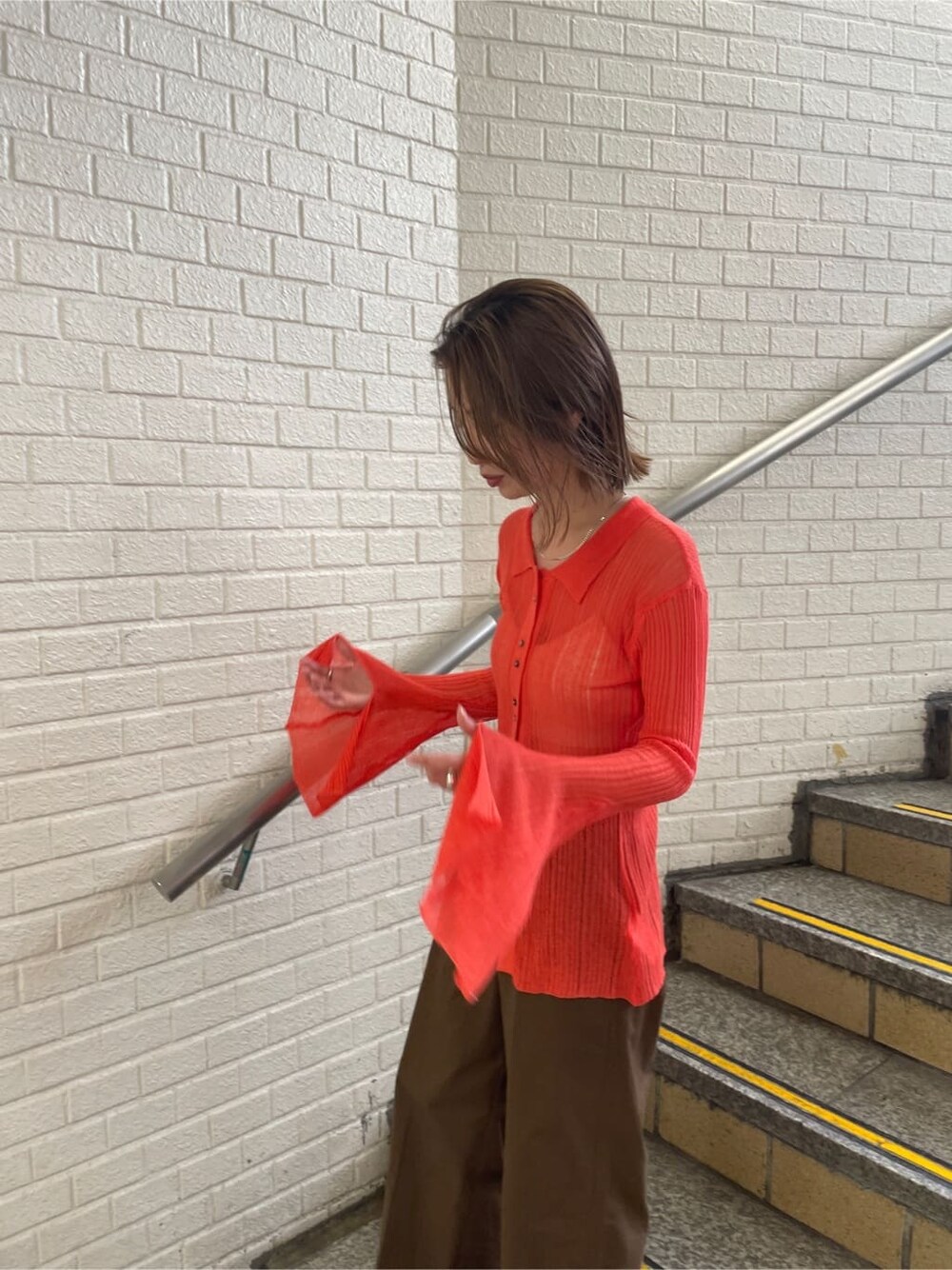 ブラウン系のチノパンツ、オレンジ系のカーディガン/ボレロを着用したレディースの夏コーディネートの3枚目の写真