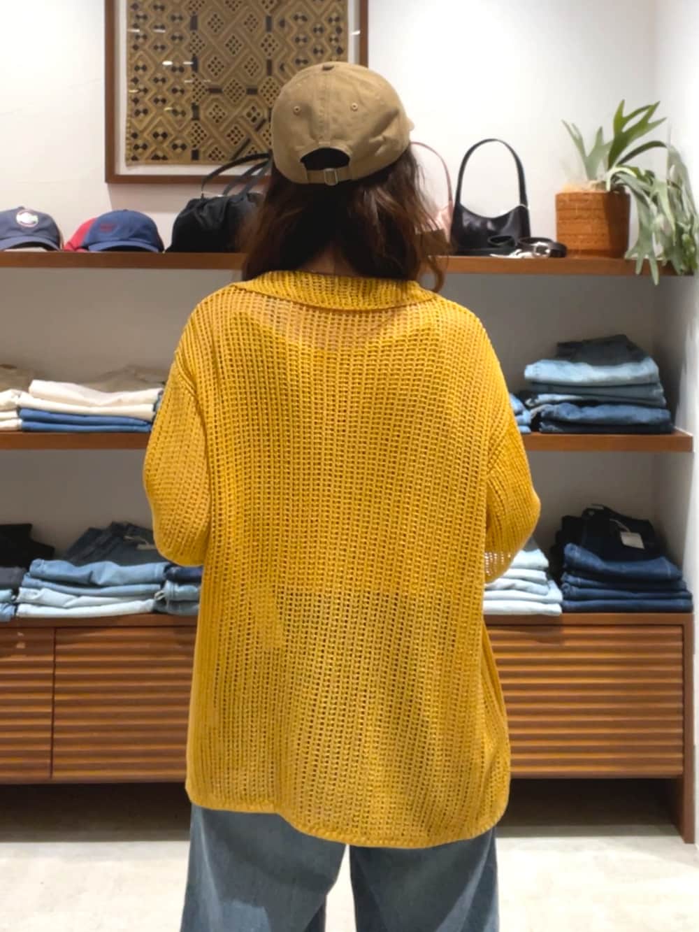 オレンジ系のカーディガン/ボレロ、ブルー系のデニムパンツを着用したレディースの春コーディネートの6枚目の写真