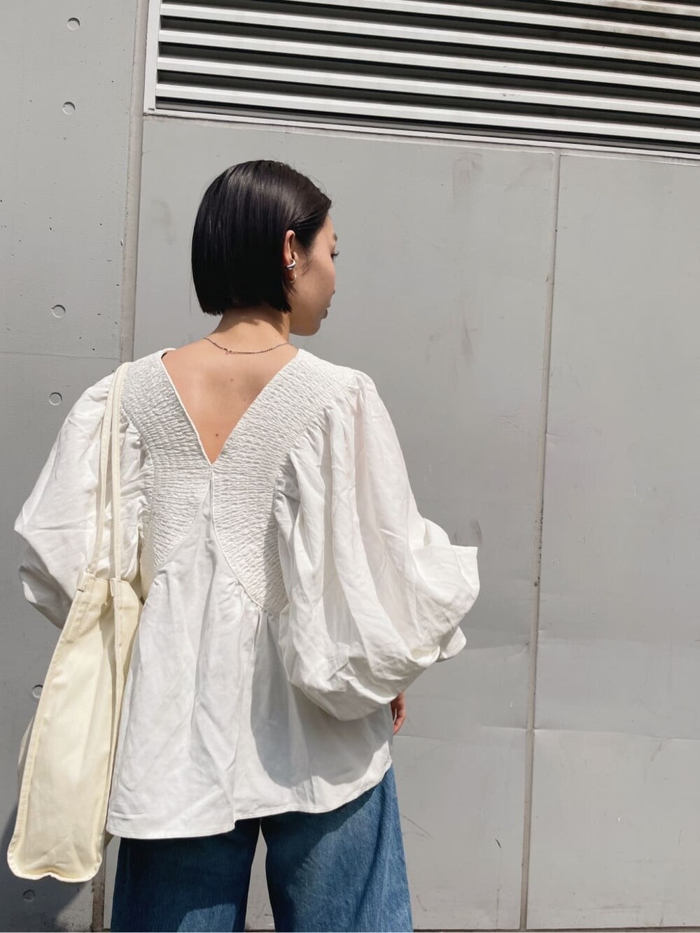 ホワイト系のシャツ/ブラウス、ブラック系のサンダル、ブルー系のデニムパンツを着用したレディースの春コーディネートの2枚目の写真