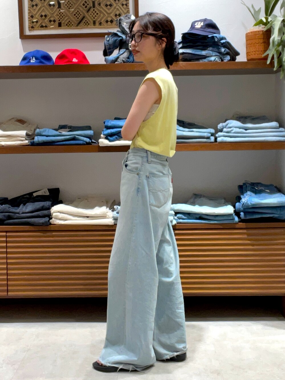 イエロー系のタンクトップ、ブルー系のデニムパンツを着用したレディースの夏コーディネートの2枚目の写真