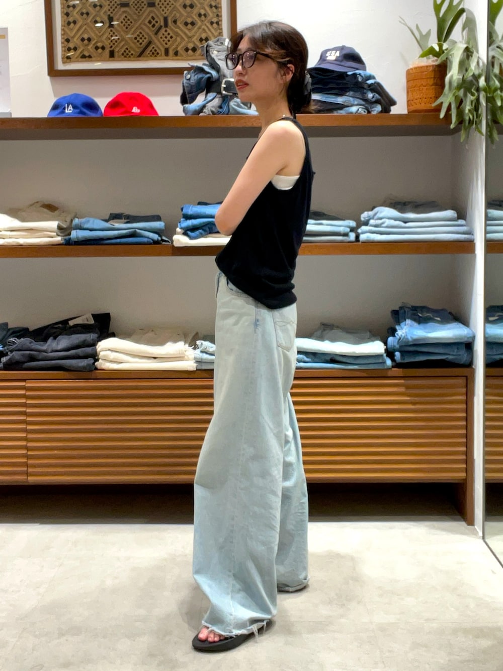 ブラック系のタンクトップ、ブルー系のデニムパンツを着用したレディースの夏コーディネートの2枚目の写真