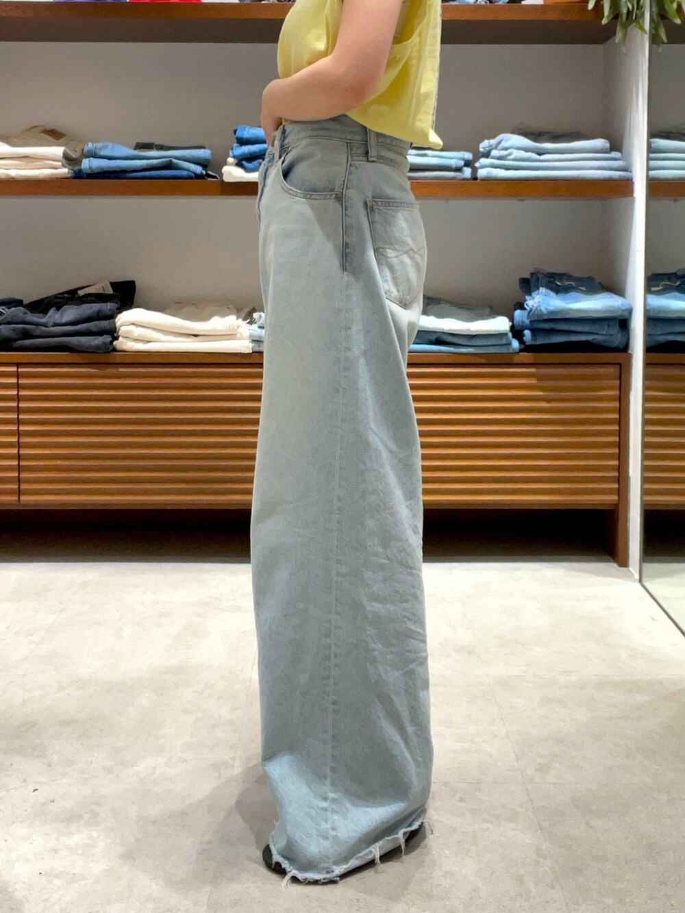 イエロー系のタンクトップ、ブルー系のデニムパンツを着用したレディースの夏コーディネートの7枚目の写真