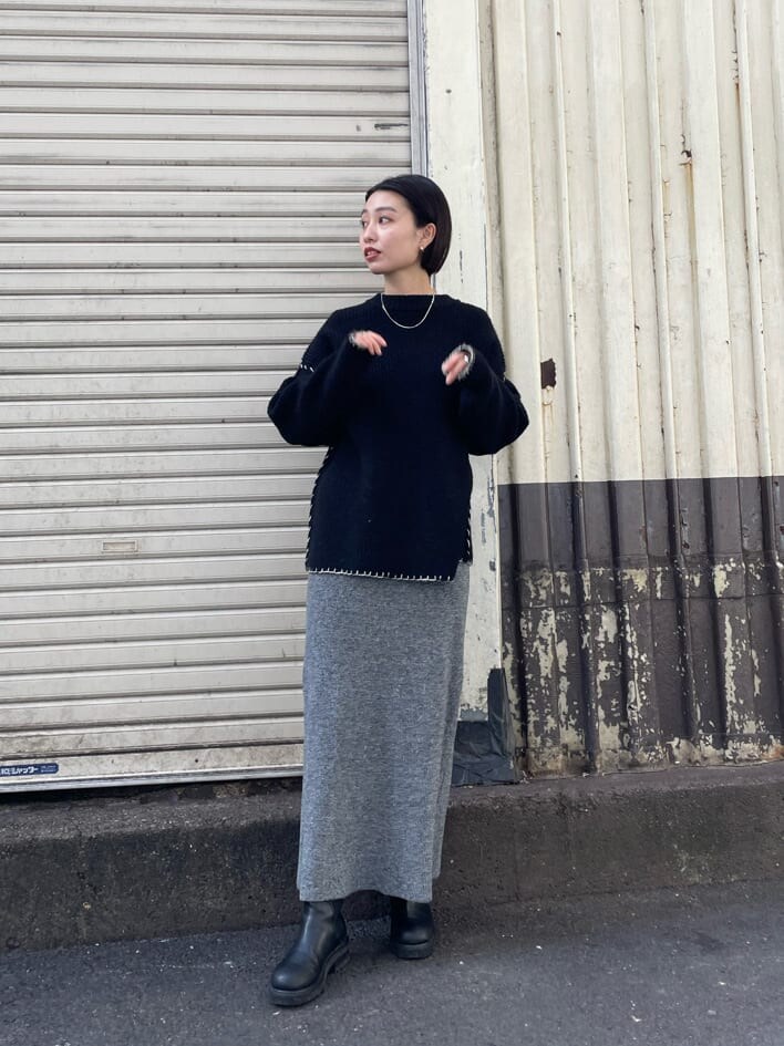 グレー系のスカート、ブラック系のニット/セーターを着用したレディースの冬コーディネートの2枚目の写真