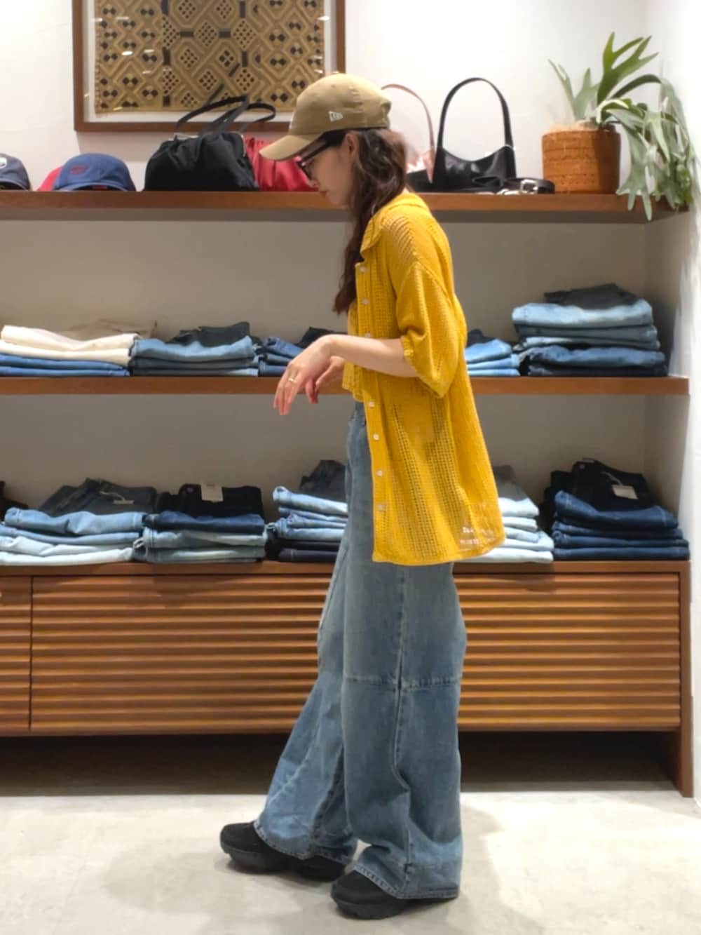 オレンジ系のカーディガン/ボレロ、ブルー系のデニムパンツを着用したレディースの春コーディネートの2枚目の写真