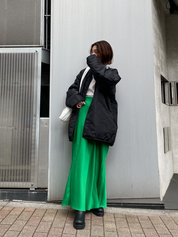 グリーン系のスカート、ブラック系のブーツ、ホワイト系のエコバッグ/サブバッグを着用したレディースの秋コーディネートの2枚目の写真