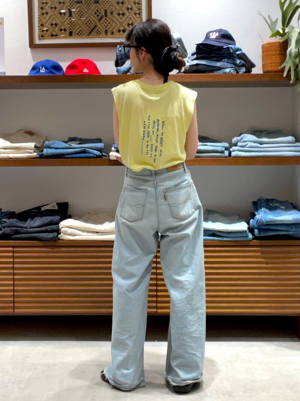 イエロー系のタンクトップ、ブルー系のデニムパンツを着用したレディースの夏コーディネートの3枚目の写真