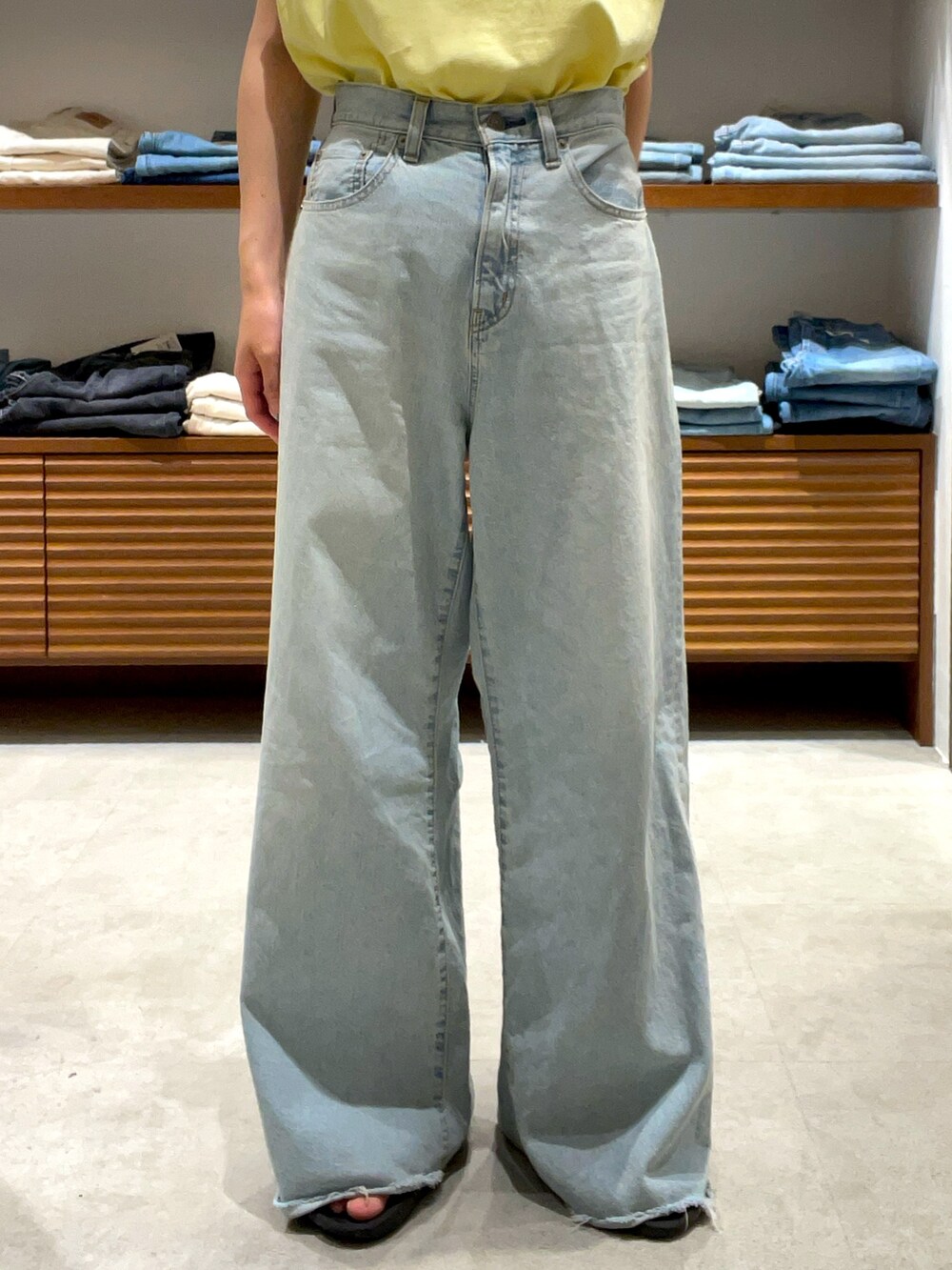 イエロー系のタンクトップ、ブルー系のデニムパンツを着用したレディースの夏コーディネートの6枚目の写真