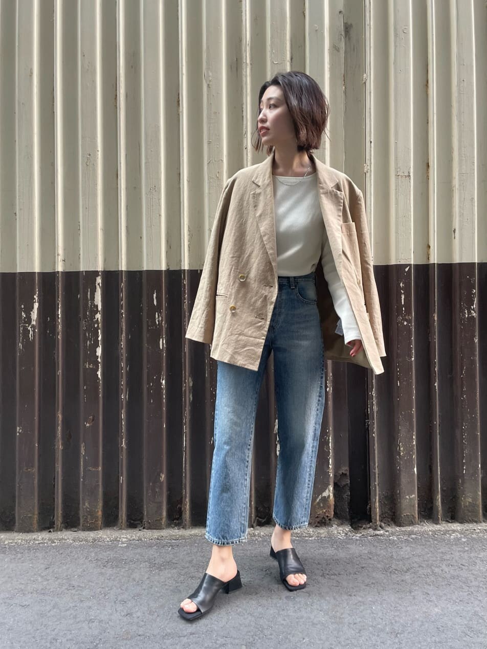 ベージュ系のテーラードジャケット、ホワイト系のTシャツ/カットソー、ブルー系のデニムパンツを着用したレディースの春コーディネートの2枚目の写真