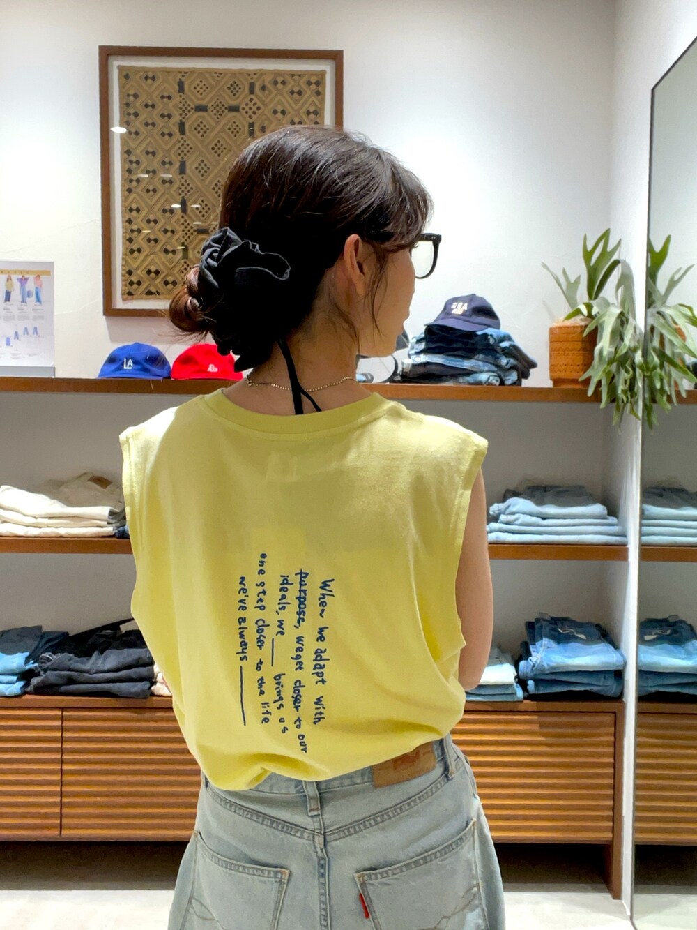 イエロー系のタンクトップ、ブルー系のデニムパンツを着用したレディースの夏コーディネートの5枚目の写真