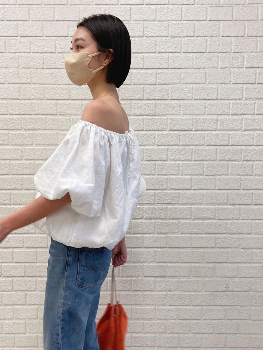 ブルー系のデニムパンツ、ホワイト系のシャツ/ブラウス、オレンジ系のハンドバッグを着用したレディースの春コーディネートの2枚目の写真