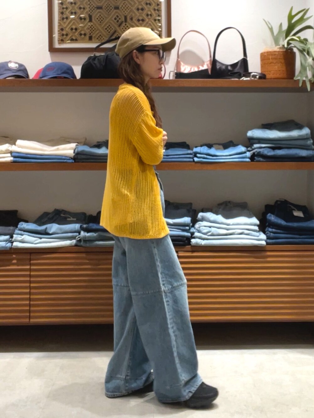 オレンジ系のカーディガン/ボレロ、ブルー系のデニムパンツを着用したレディースの春コーディネートの4枚目の写真