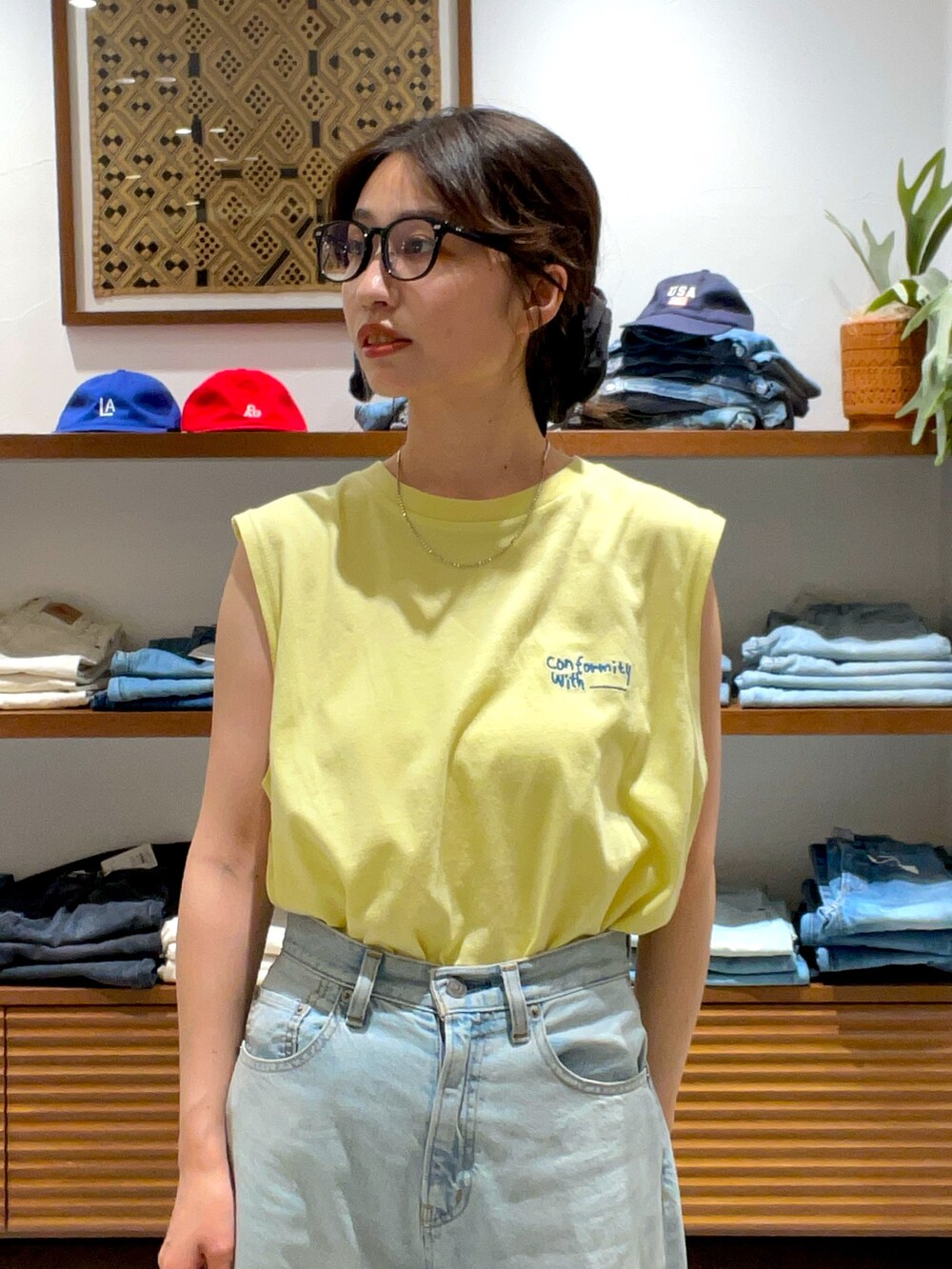 イエロー系のタンクトップ、ブルー系のデニムパンツを着用したレディースの夏コーディネートの4枚目の写真