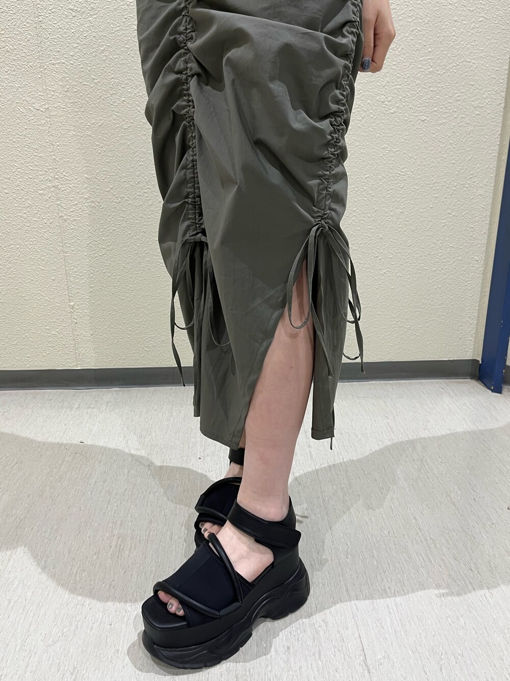 グリーン系のワンピース、ブラック系のサンダル、ブラック系のネックレスを着用したレディースの春コーディネートの6枚目の写真