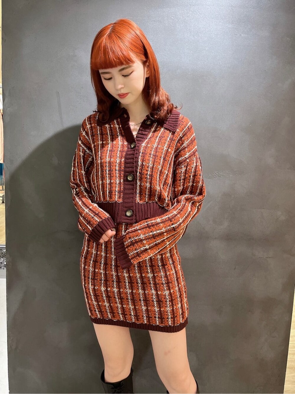 レッド系のカーディガン/ボレロ、レッド系のスカート、ブラック系のブーツを着用したレディースの秋コーディネートの2枚目の写真