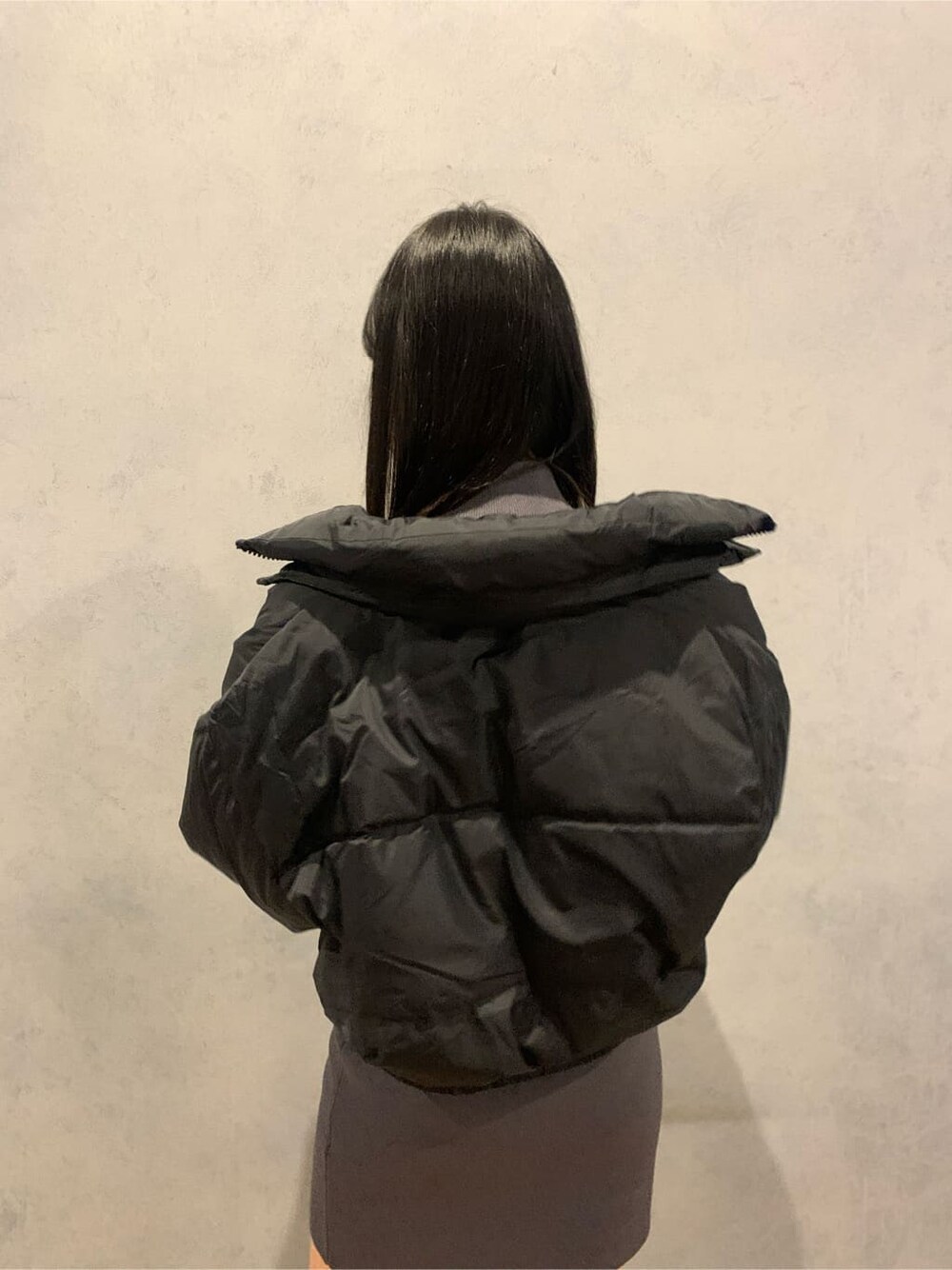 グレー系のワンピース、ブラック系のダウンジャケット/コート、ブラック系のブーツを着用したレディースの冬コーディネートの4枚目の写真