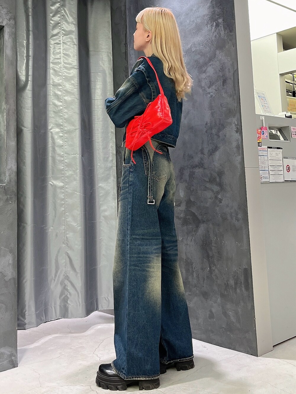 ブルー系のデニムパンツ、ブルー系のデニムジャケット、ブラック系のブーツを着用したレディースの秋コーディネートの2枚目の写真