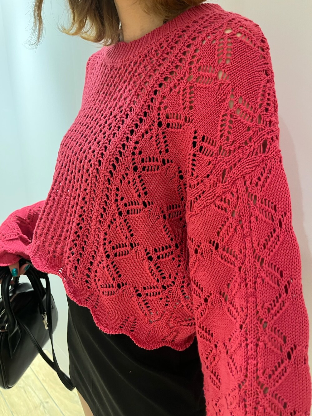 ピンク系のニット/セーター、ブラック系のハンドバッグ、ホワイト系のブーツを着用したレディースの冬コーディネートの4枚目の写真