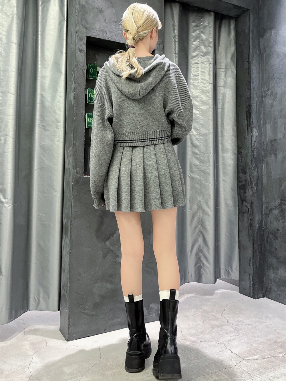 グレー系のスカート、グレー系のニット/セーター、ブラック系のブーツを着用したレディースの秋コーディネートの3枚目の写真